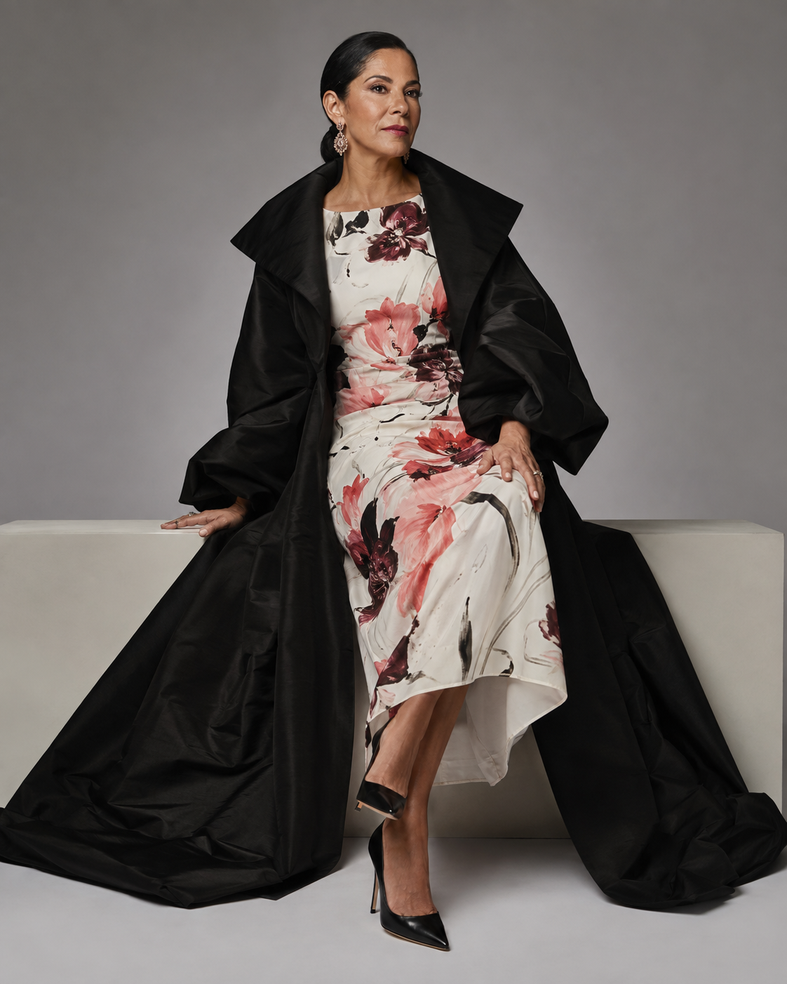 Woman in a dramatic black coat and floral column dress